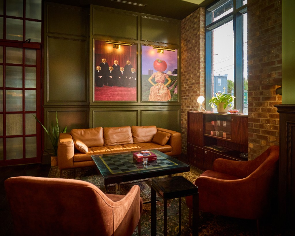 Archie's lounge with caramel leather seating, a checkerboard coffee table, framed surreal artwork, and green panelled walls